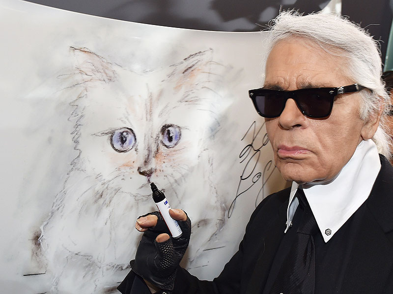 Karl Lagerfeld poses next to a painting of his cat